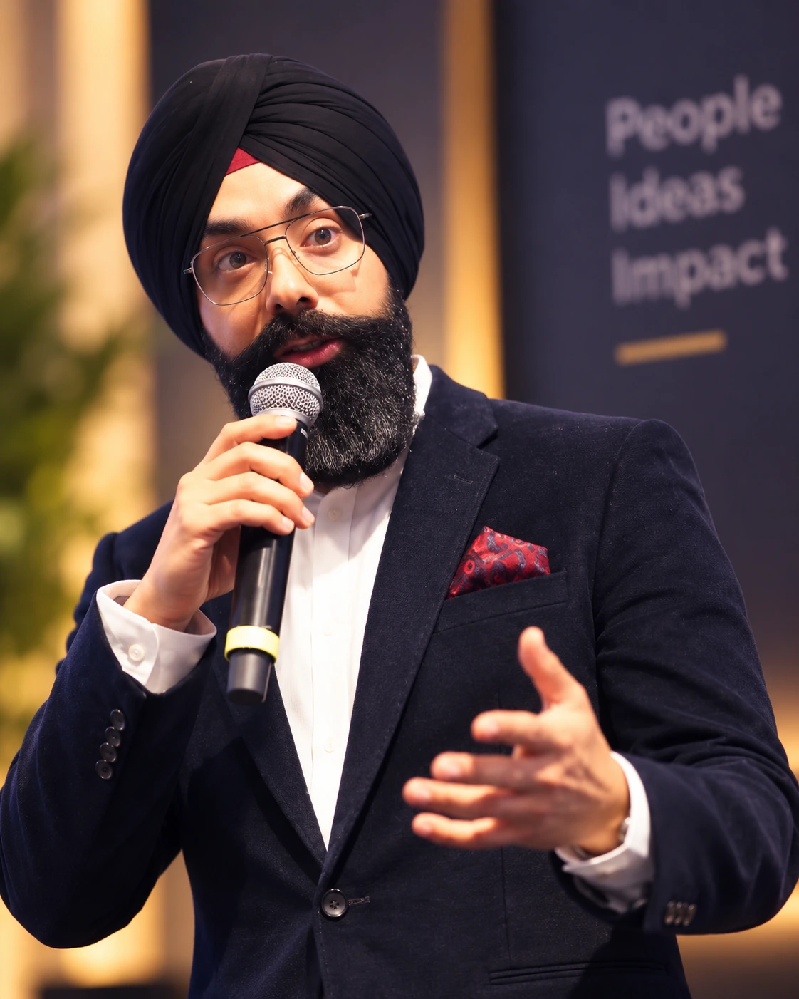 Navdeep Chhabra speaking into a microphone and gesturing toward his audience.